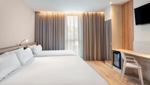 A hotel room with two beds, a desk, a TV, and a window with curtains. - B&B HOTEL Sevilla Bormujos (Bormujos)