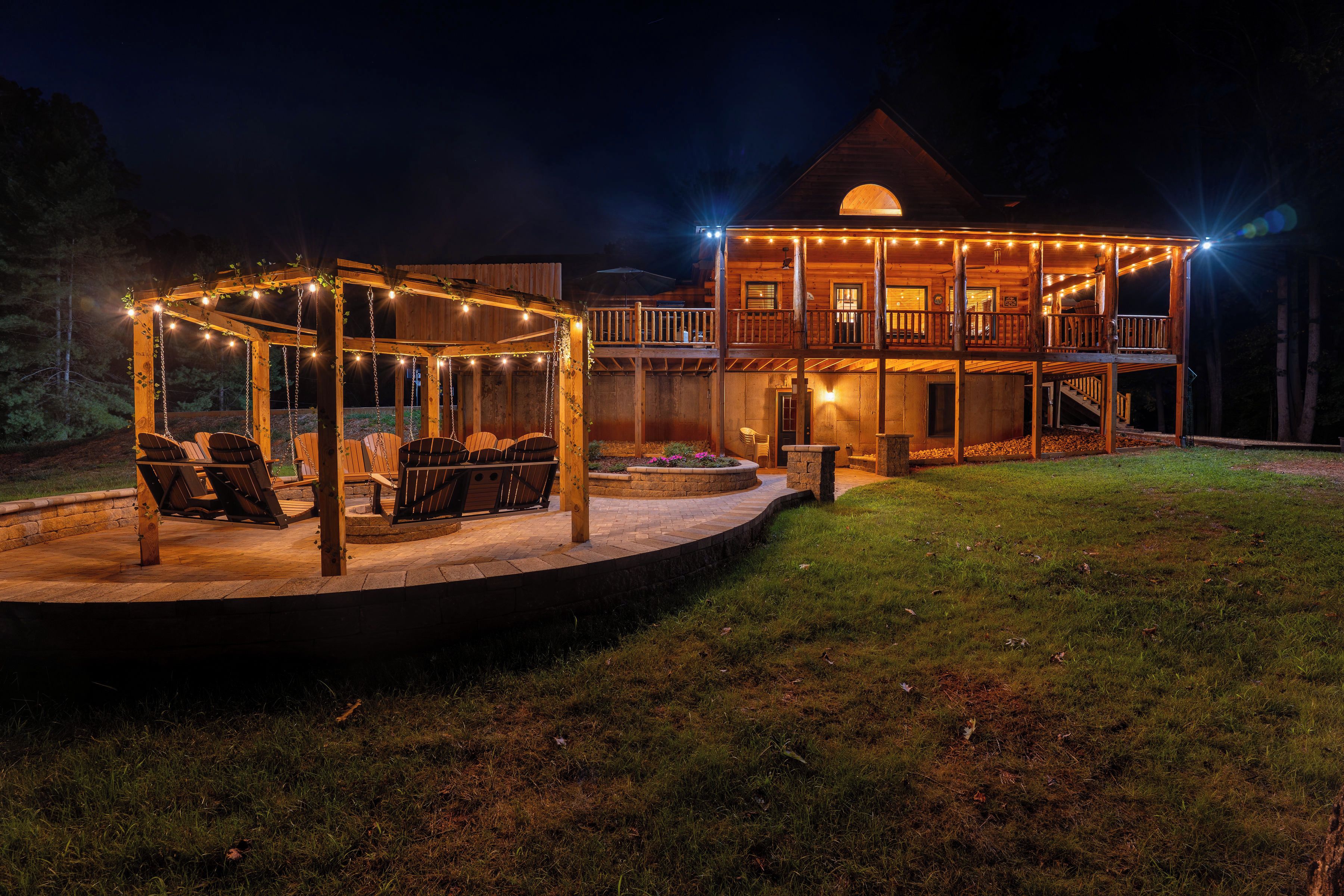 A two-story wooden cabin with a covered outdoor seating area and a deck.