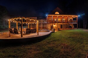 A two-story wooden cabin with a covered outdoor seating area and a deck.