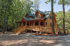 A log cabin with a wooden deck, a staircase, and a 'Welcome' sign.