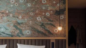 Ein Schlafzimmer mit einem Bett, einer Wandleuchte, einem Nachttisch und einem Holzkopfteil.