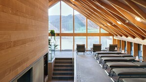 Un intérieur moderne agrémenté de poutres en bois, d’une cheminée et d’un coin salon offrant une vue sur l’extérieur.