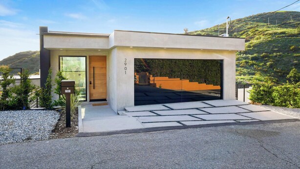 Una casa moderna de dos pisos amb garatge, carril d'accés i una bústia.
