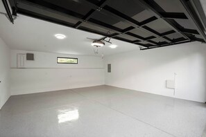 A spacious, well-lit room with a polished floor, a ceiling fan, recessed lighting, and a window.