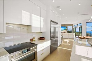 A modern kitchen with stainless steel appliances, white cabinetry, and a large island.