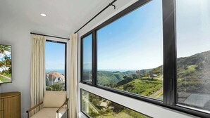 Habitació amb un gran finestral que ofereix vistes a turons verds i un edifici modern.