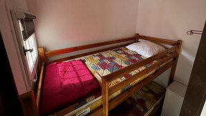 A small, single-bed room with a wooden frame, a colorful quilt, and a white pillow. There is a small white cabinet against the wall. - Cozy Studio with Pool Access, Private Garden, and Close to Beach - Argelès-sur-Mer (Argelès-sur-Mer)