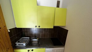 A compact kitchen with a washing machine, a sink, and a dish rack. - Cozy Studio with Pool Access, Private Garden, and Close to Beach - Argelès-sur-Mer (Argelès-sur-Mer)
