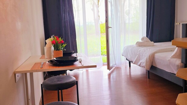 Une chambre d’hôtel moderne, équipée d’un lit, d’un bureau avec une chaise et offrant une vue sur l’extérieur.