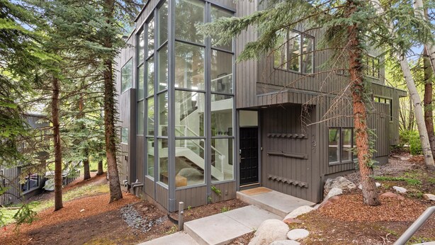 Een moderne chalet met grote glasramen, een houten gevel en een stenen trap naar de ingang.
