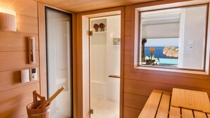 Interior de madera con vista al mar a través de una ventana, una mesa de madera y un cubo de madera con una cuchara.