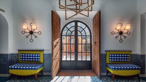A hallway with two yellow armchairs, a geometric chandelier, and a large arched window. - My Rental Homes | Villa Gem with sea view and pool (Soller)