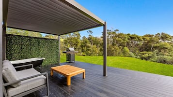 Enjoy outdoor dining and cooking on the covered deck, surrounded by lush greenery.