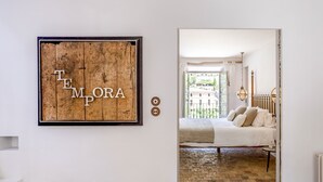 A bedroom with a bed, a view of the outside, and a wooden sign on the wall.
