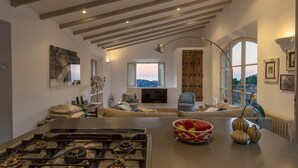 A spacious living room with a modern kitchen, large windows, and a cozy seating area.