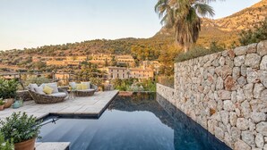 A stone wall, a wicker lounge chair, and a view of a village.