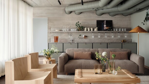 A modern living room with a grey sofa, wooden chairs, and a coffee table. There is a kitchen area with cabinets and a TV above the counter. - Bob W Helsinki Kamppi (Helsinki)