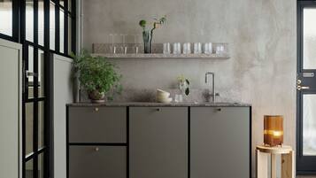 Cocina moderna con gabinetes grises, un lavamanos de acero inoxidable y un taburete de madera con una lámpara.