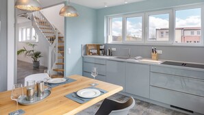 A modern kitchen with a wooden dining table, grey cabinets, and a large window. - Comfortable vacation home Neukamp 17C Seehütte in an idyllic location near Putbus (Putbus)
