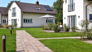 A residential area with houses, a paved walkway, and a grassy lawn. - Comfortable vacation home Neukamp 17C Seehütte in an idyllic location near Putbus (Putbus)