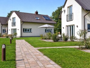 A residential area with houses, a paved walkway, and a grassy lawn.