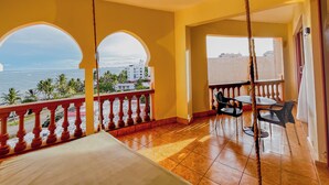 A balcony with a view of the sea and palm trees, a table with chairs, and a hanging rope. - Kuzuri Kwetu Beachfront Apartments (Mombasa)