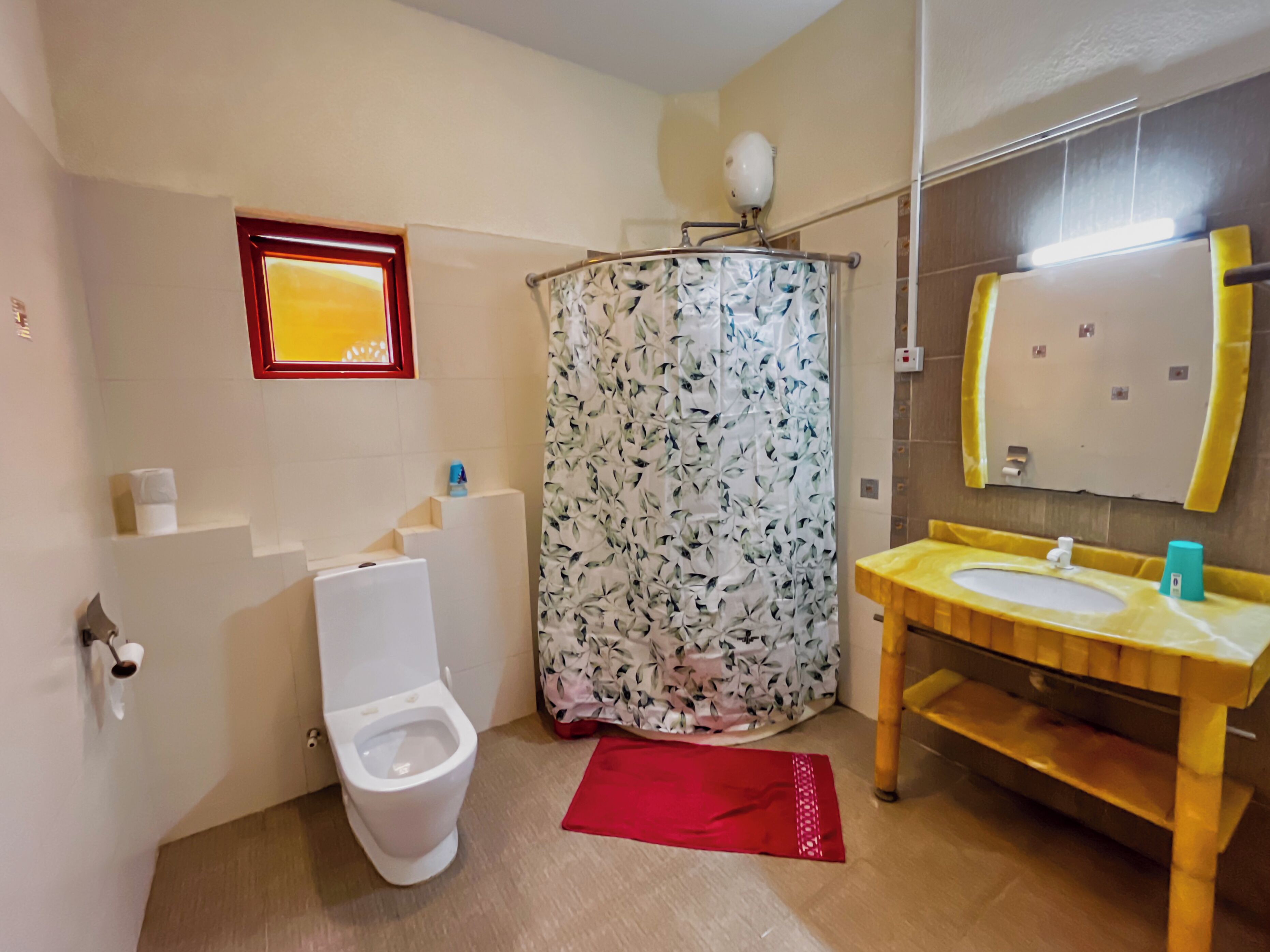 A bathroom with a toilet, a shower curtain, a sink, and a mirror.
