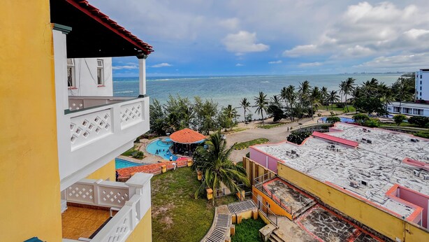 A hotel with a rooftop pool, a view of the ocean, and a tropical setting with palm trees. - Kuzuri Kwetu Beachfront Apartments (Mombasa)