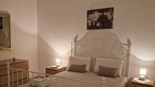 A neatly arranged bedroom with a bed, bedside tables, a nightstand, a dresser, a mirror, and a world map on the wall. - Isabel house (Napoli)