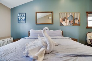 A hotel room with a bed, a mirror, a wall with a motivational quote, and a window.