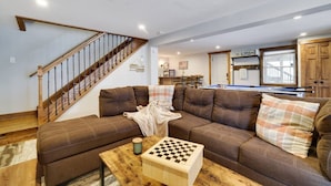 A living room with a brown sofa, wooden coffee table, and a chessboard. - Lakeview Escape with Hot Tub, lake, & Ski (Lake Harmony)