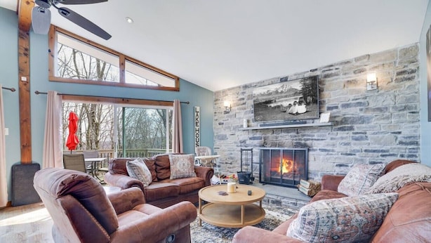 A cozy living room with leather sofas, a fireplace, and a stone wall. - Lakeview Escape with Hot Tub, lake, & Ski (Lake Harmony)