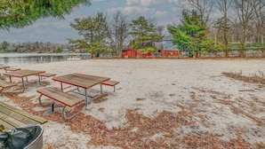 A sandy beach with picnic tables and a red building in the background. - Lakeview Escape with Hot Tub, lake, & Ski (Lake Harmony)