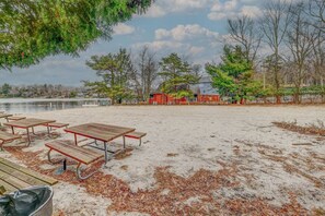 Ein Sandstrand mit Picknicktischen und einem roten Gebäude im Hintergrund.