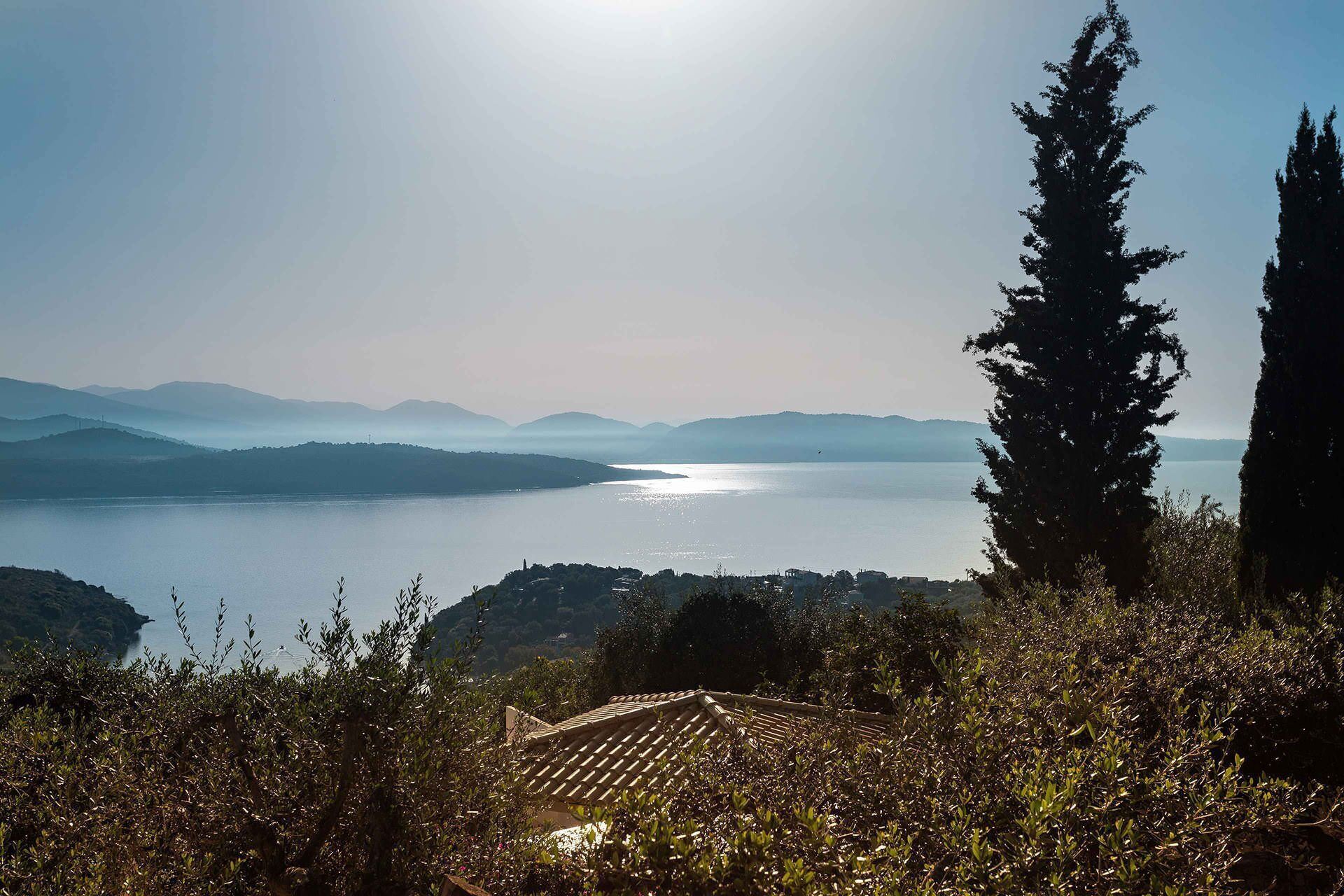 Ein Weinberg mit terrassenförmig angelegten Feldern, mit Blick auf einen stillen See und entfernte Berge.