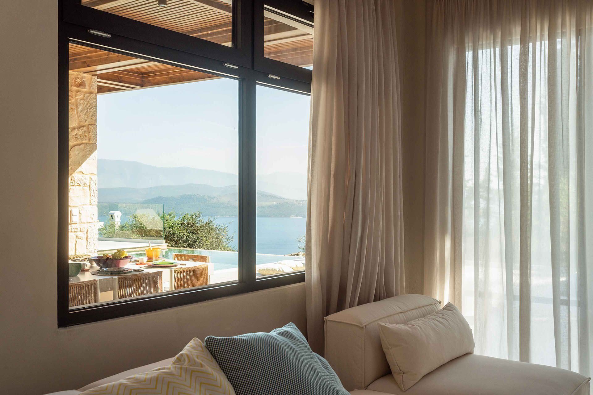 Quarto com uma grande janela com vista para uma piscina e uma paisagem panorâmica de montanhas e um corpo de água.