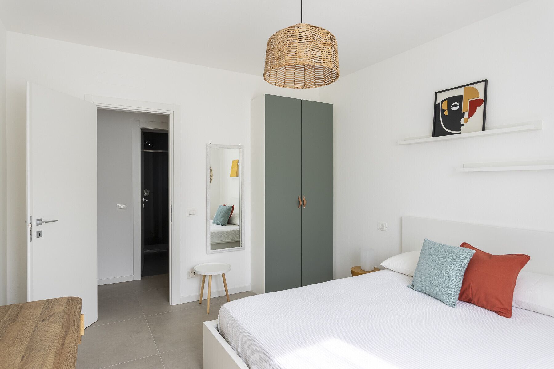 A bedroom with a bed, a wardrobe, a mirror, and a hanging light fixture.