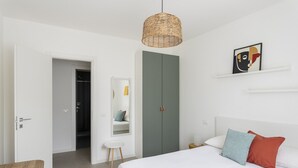 A bedroom with a bed, a wardrobe, a mirror, and a hanging light fixture. - Apartment MoKi in Moniga del Garda (Moniga del Garda)