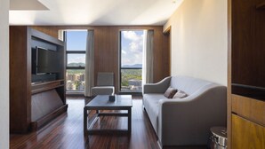 A modern living room with a flat-screen TV, a sofa, a coffee table, and a view of a cityscape through large windows. - SSAW Boutique Hotel DeXin - Near Mount Mogan (Huzhou)