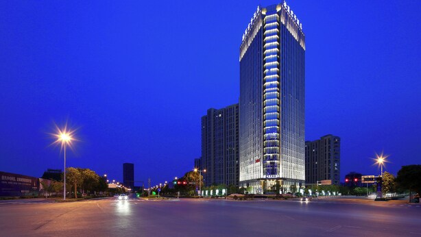 A high-rise hotel with a modern design, featuring a prominent vertical structure and illuminated windows. - SSAW Boutique Hotel DeXin - Near Mount Mogan (Huzhou)
