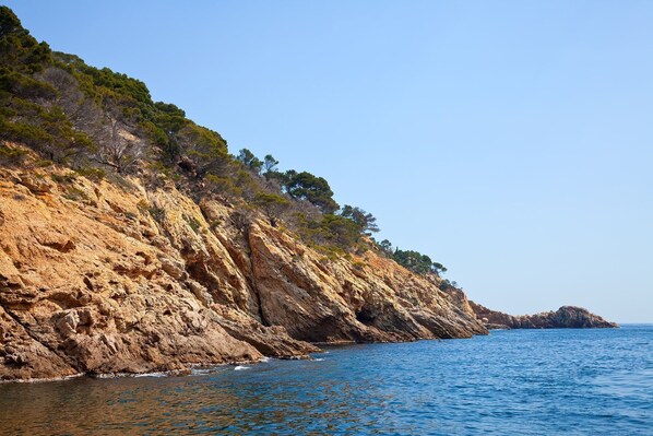 A coastal landscape with rocky cliffs and a clear blue sea.