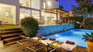 A modern house with a swimming pool, outdoor seating, and a covered patio area. - My Rental Homes | Villa Luminosa with private pool and garden (Palafrugell)