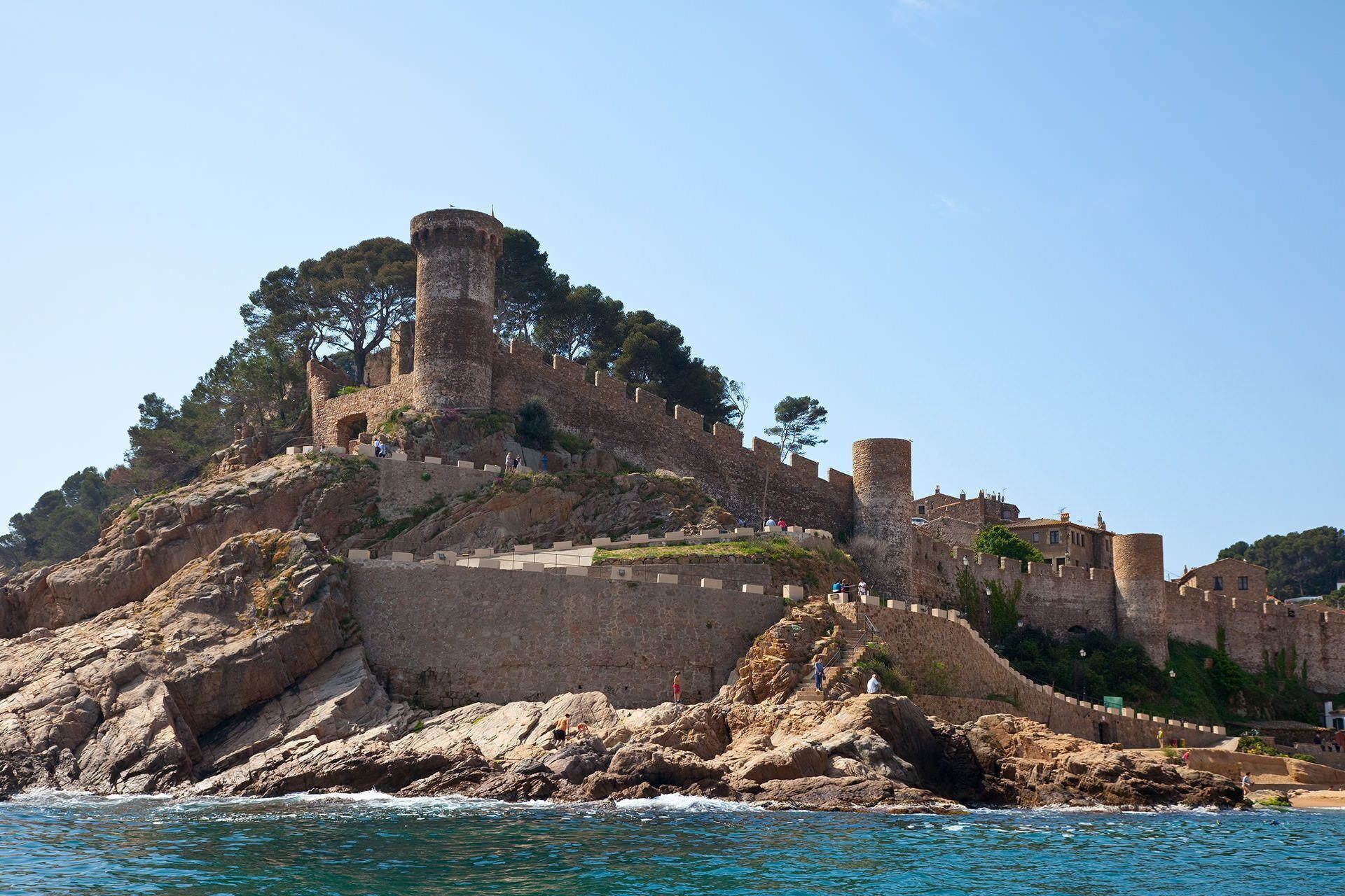 Une forteresse historique en pierre, dotée d’une tour imposante, située sur une côte rocheuse.