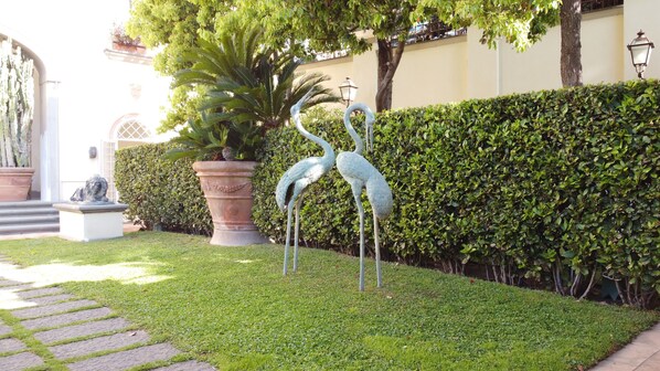 A garden with a large planter, a statue of a bird, and a hedge. - Casa Raiola Luxury rooms (Ercolano)