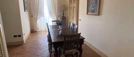 A dining area with a large wooden table, chairs, and a chandelier.