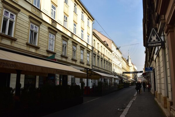 A street with buildings, a pedestrian walkway, and a sign for 'Garastria'.