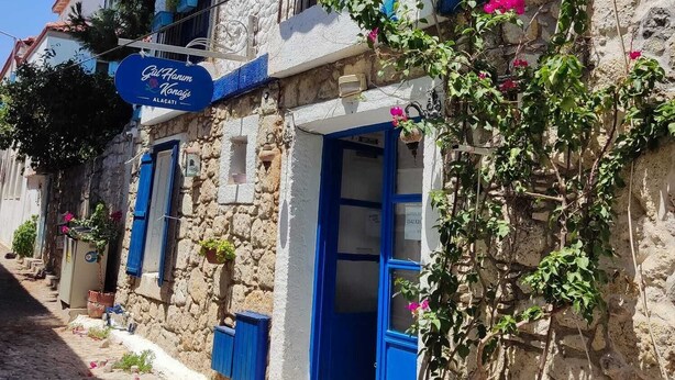 A stone building with blue shutters and a sign for "Gül Hanım Konak." - Gül Hanım Konağı (Cesme)