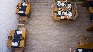 A restaurant with multiple wooden tables set for dining, arranged on a herringbone patterned floor. - Gül Hanım Konağı (Cesme)