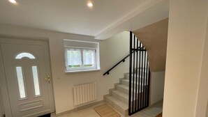 A staircase with a black handrail leading to an upper floor, a white door with a glass panel, a window with a view of greenery, and a radiator on the wall. - L'Echappée Verte, your nature cocoon in the heart of Alsace Verte (Dambach)