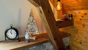 A wooden interior with a stone fireplace, a wooden shelf with decorative items, a wall-mounted light, and a clock. - L'Echappée Verte, your nature cocoon in the heart of Alsace Verte (Dambach)